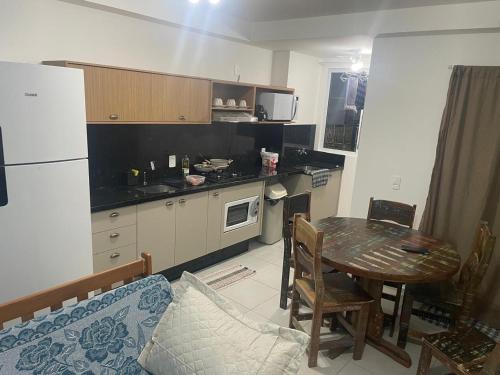 a kitchen with a table and a kitchen with a refrigerator at Apartamento Itapoá in Itapoa
