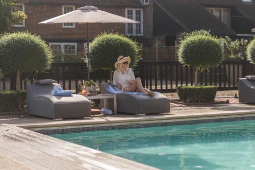 a woman sitting in a chair next to a swimming pool at Whitmoor Farm in Guildford