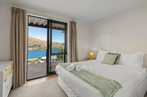 a bedroom with a large bed with a large window at Goldrush Way 4BR 3BA Lake & Mountain Views in Frankton Wharf