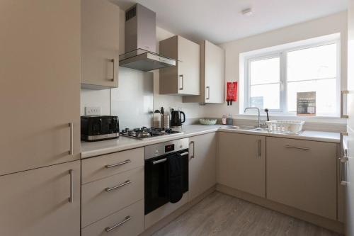 a kitchen with white cabinets and a stove top oven at Runcorn Spacious Modern 3 bedroom House, 4 beds, On site Parking, Long stay deals in Runcorn