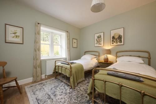 two beds in a room with a window at Church Cottage in Lochend