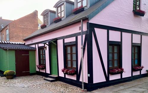 a pink and white building with windows on a street at Riberdyb in Kolding
