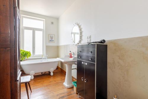 a bathroom with a bath tub and a sink and a bath tub at Jolie Maison en Bois Authentique in Dunkerque