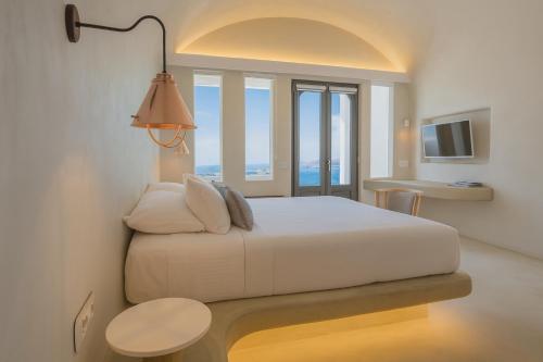 a bedroom with a large white bed with a window at Chic Hotel Santorini in Firostefani