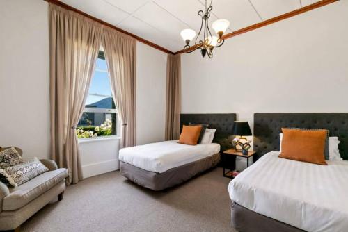 a bedroom with two beds and a couch and a window at Historic Stone Cottage Apt 1- spa - 3 min from town in Queenstown