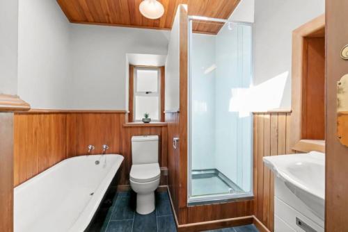 a bathroom with a tub and a toilet and a sink at Historic Stone Cottage Apt 1- spa - 3 min from town in Queenstown