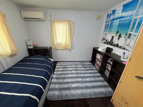 ein kleines Schlafzimmer mit einem Bett und einem gestreiften Teppich in der Unterkunft ゲストハウス宮崎 guesthouse miyazaki バックパッカー向け個室旅人宿 P有宮崎駅1km喫煙者不可 in Miyazaki
