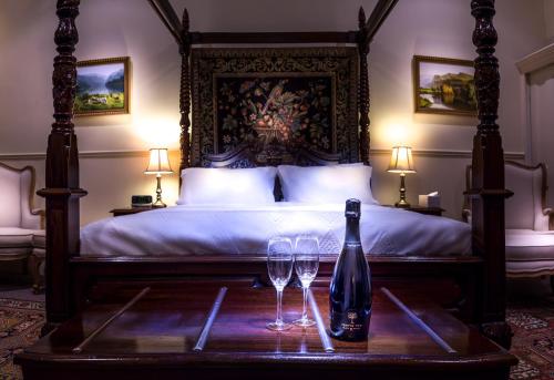 a bed with a bottle of wine and two glasses on a table at Fothergills of Fremantle in Fremantle