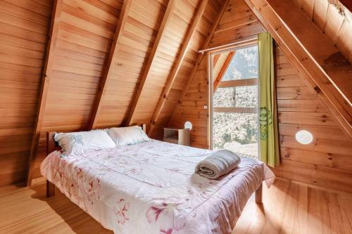 a bed in a wooden room with a window at Chalé Refúgio Vô Chico in Alfredo Wagner