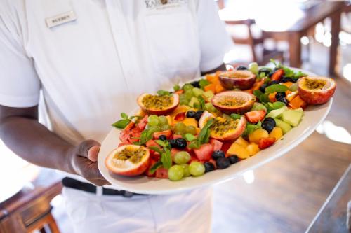 侯斯普瑞特Karongwe - River Safari Lodge的一名男子手捧一盘水果和蔬菜