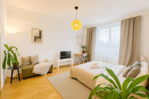 a white bedroom with a bed and a couch at Budovatelska Apartment in Bratislava