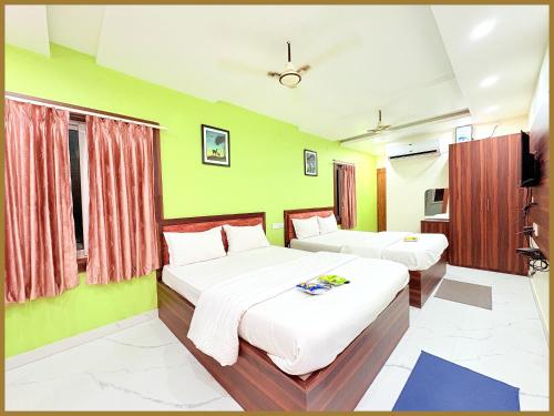 deux lits dans une chambre aux murs verts dans l'établissement Baliapand Road NewParwati Palace Inn- #Fully Air Condition with All Luxury Luxuary Rooms #Balcony Free Wifi # Parking & Lift Facilities- Best Luxuary Hotel In Puri, à Purî