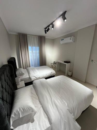 une chambre d'hôtel avec deux lits avec des draps blancs dans l'établissement شقة متكاملة بجوار ملعب الجوهرة, à Djeddah