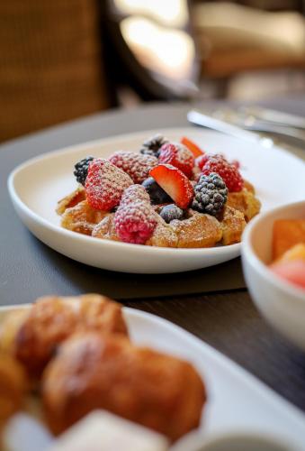 a plate of waffles with fruit on top on a table at Grand Hotel Karel V in Utrecht