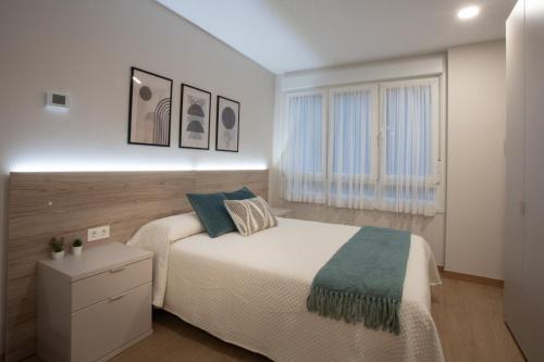 ein weißes Schlafzimmer mit einem Bett und einem Fenster in der Unterkunft ITURRIONDO by Urdaibai Experience in Gernika