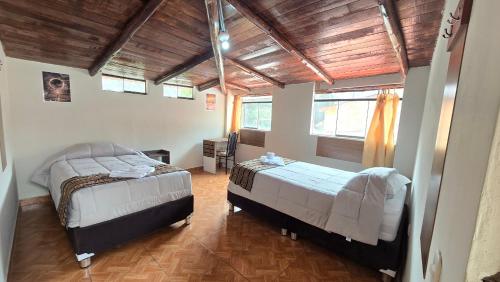 a bedroom with two beds and a wooden ceiling at Refugio Sagrado Boutique in Ollantaytambo