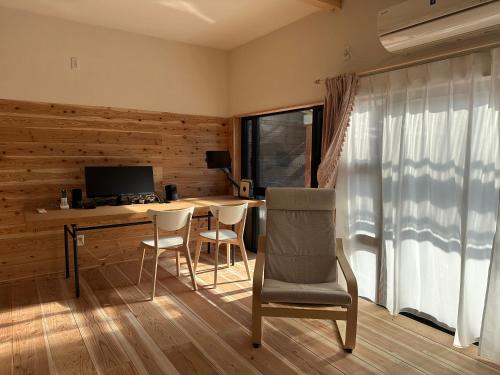 a room with a desk with chairs and a television at ぷらたなすYufuin Kinrin Lake Private Tiny Coffee Villa in Yufu