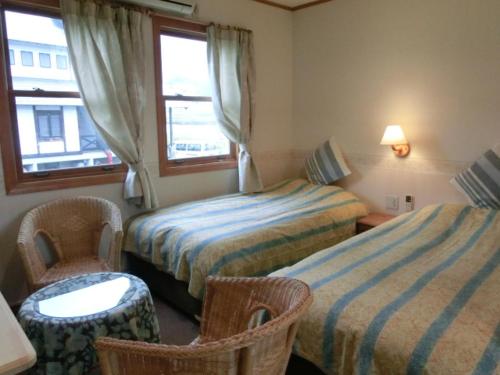 a hotel room with two beds and chairs and a window at Pension Come in Minami Uonuma