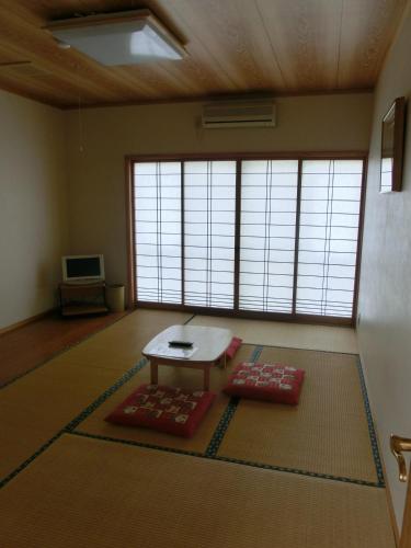 a living room with a table and a room with windows at Pension Come in Minami Uonuma