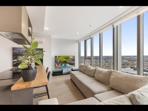 a living room with a couch and large windows at Gorgeous High-Rise Unit with Sky Bar Pool and Gym in Melbourne