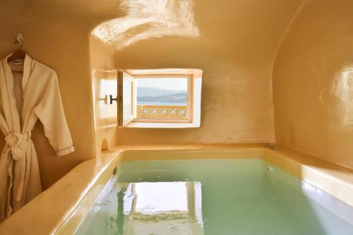 a bath tub in a bathroom with a window at OIA UNIQUE HOMES by K&K in Oia
