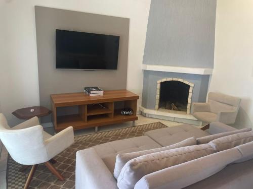 ein Wohnzimmer mit einem Sofa, einem TV und einem Kamin in der Unterkunft casa no centro proximo ao mar in Xangri-lá