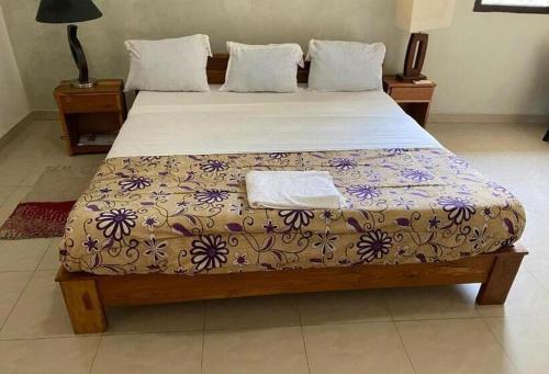 a bedroom with a large bed with a floral bedspread at Marsu hotel in Cap Skirring