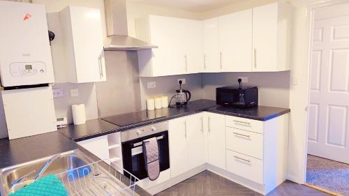 a kitchen with white cabinets and a black microwave at Peaceful, Cosy and Central Stay in Nottingham in Nottingham