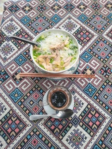 eine Schüssel Essen und eine Tasse Kaffee auf dem Tisch in der Unterkunft An' Home Mai Chau in Mai Châu