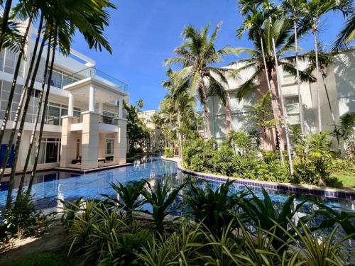 a swimming pool in front of a building with palm trees at Hua Hin Blue Lagoon Island Villa A Family Paradise in Ban Nong Chaeng