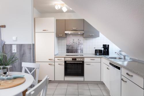 Una cocina con gabinetes blancos y un fregadero y una mesa. en Wenkendeck, en Fehmarn
