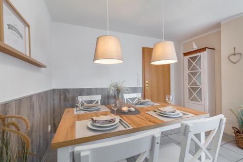 cocina con mesa de comedor con sillas blancas en Wenkendeck, en Fehmarn