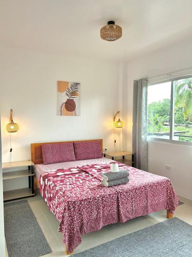 a bedroom with a bed with a red blanket and a window at Coconut Inn in Moalboal