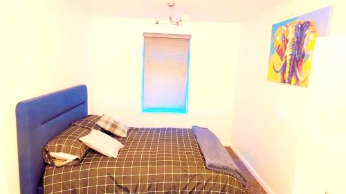a bedroom with a bed with a blue headboard and a window at Peaceful, Cosy and Central Stay in Nottingham in Nottingham