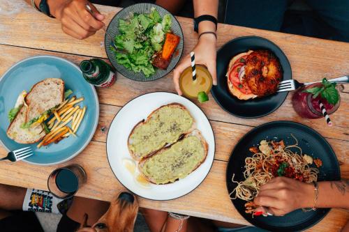 un groupe de personnes assises autour d'une table en bois avec des assiettes de nourriture dans l'établissement Lay Day Hostel Canggu, à Canggu