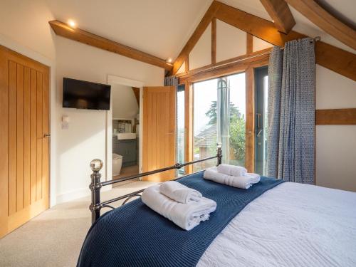 Un dormitorio con dos toallas en una cama con ventana. en Beautiful Oak-framed Devon Escape Near Dartmouth, en Stoke Fleming