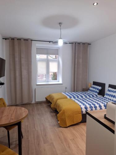 ein Schlafzimmer mit einem Bett, einem Tisch und einem Fenster in der Unterkunft Studio przy Szpitalu in Stettin