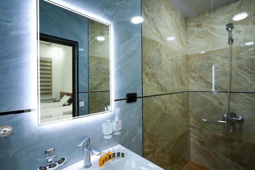 ein Badezimmer mit Waschbecken, Dusche und Spiegel in der Unterkunft Chehran Hotel in Samarkand