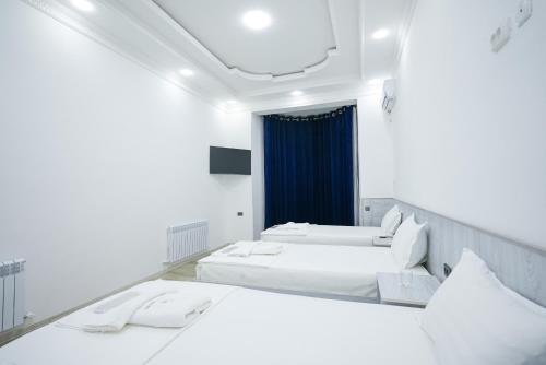 zwei Betten in einem Zimmer mit weißen Wänden in der Unterkunft Chehran Hotel in Samarkand