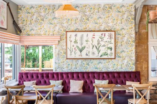 a purple velvet couch in a restaurant with floral wallpaper at Sidcot Arms in Winscombe