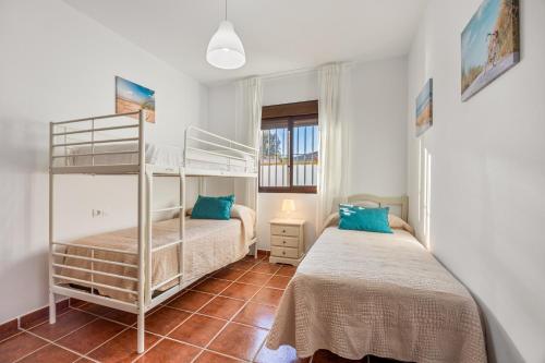 une chambre à deux lits simples avec deux lits superposés et une fenêtre dans l'établissement Brisa Marina, à Chiclana de la Frontera