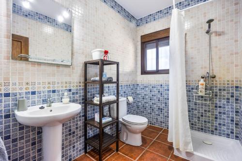 La salle de bains est pourvue de carrelage bleu, de toilettes et d'un lavabo. dans l'établissement Brisa Marina, à Chiclana de la Frontera