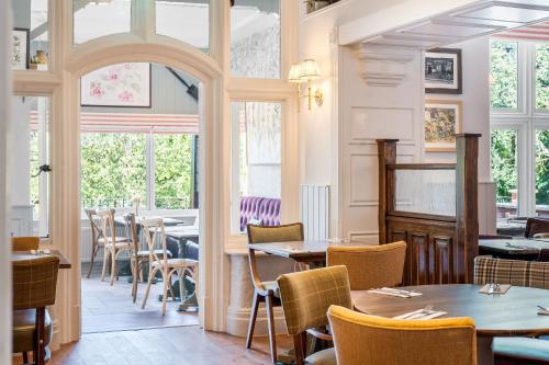 a restaurant with tables and chairs and windows at Sidcot Arms in Winscombe