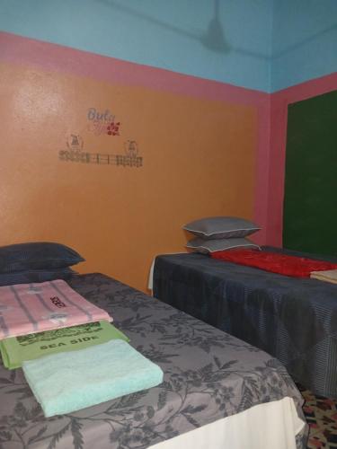 a room with two beds and a sign on the wall at SeaSide Amour Rendezvous Dormitory BEDS and Airport Shuttles in Korotogo