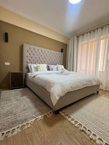 a bedroom with a large bed and a large window at Enzi Apartment Block A in Nairobi