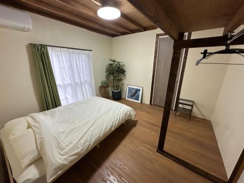 ein Schlafzimmer mit einem weißen Bett und einem Fenster in der Unterkunft 一棟貸し Cottage CASA 屋久島空港近く利便性良し 森に囲まれ静かな一軒家 in Yakushima