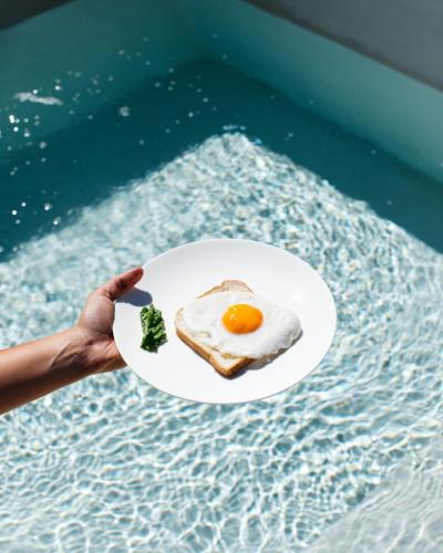 a person holding a plate with a fried egg on it at Palazzo De Noha - Boutique Hotel in Lecce