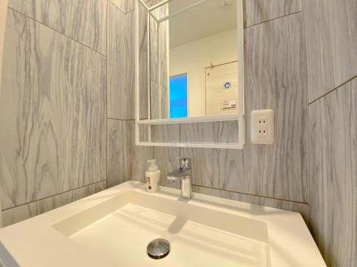 ein Badezimmer mit einem weißen Waschbecken und einem Spiegel in der Unterkunft GRANDIOSO6-B - Vacation STAY 67693v in Nakama