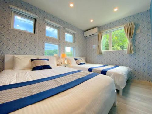 two beds in a bedroom with two windows at GRANDIOSO6-B / Vacation STAY 70977 in Inbu