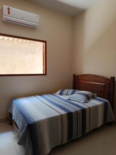 a bedroom with a bed and a window with a air conditioner at Casa Limoeiro in Pirenópolis